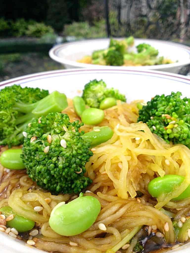 spaghetti squash with edamame, broccoli, and sesame sauce and seeds in a bowl