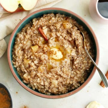 crock pot apple cinnamon oatmeal in a bowl with a spoon on a counter
