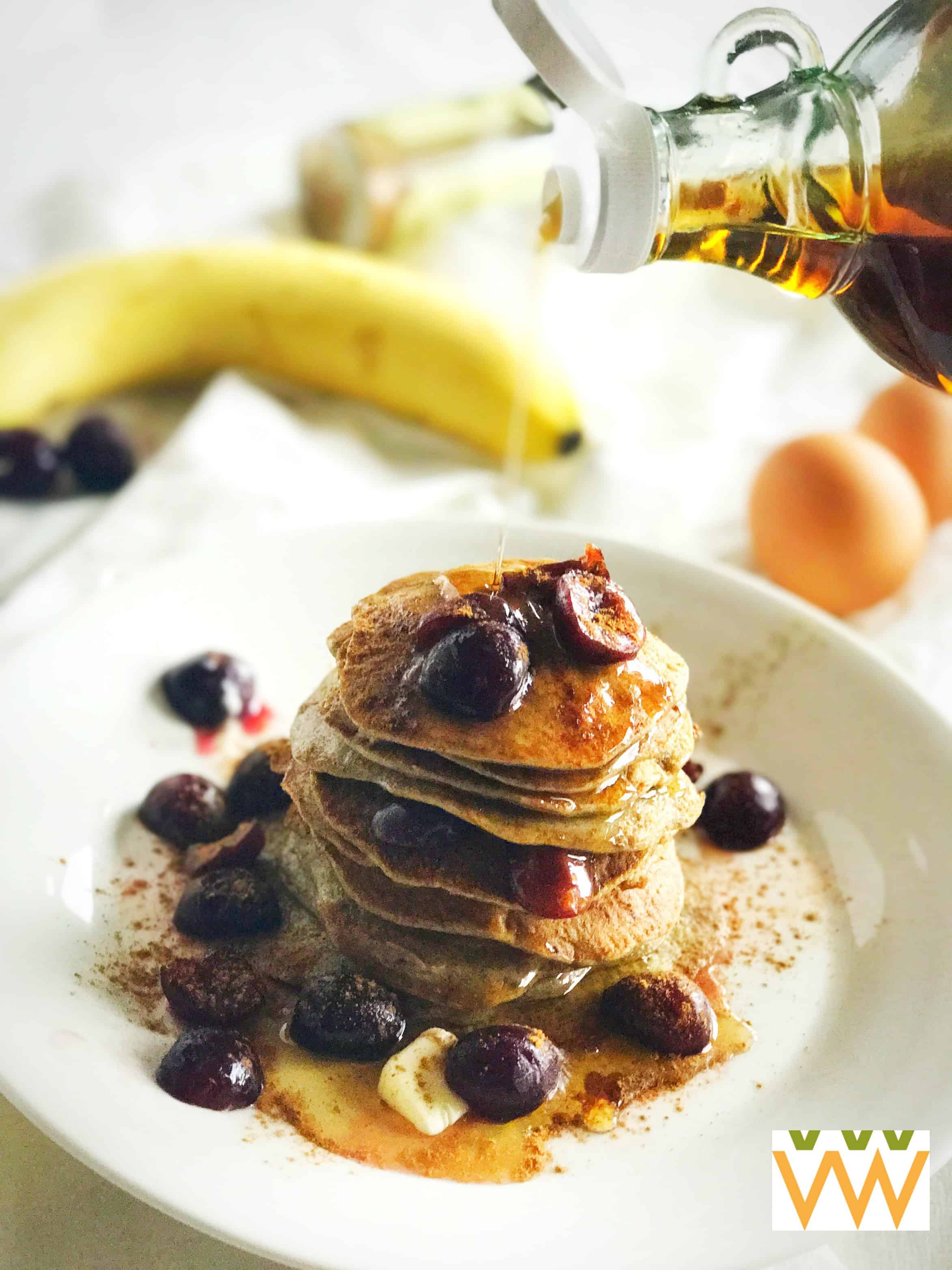 A stack of flourless pancakes in a with maple syrup being poured on top of it. 