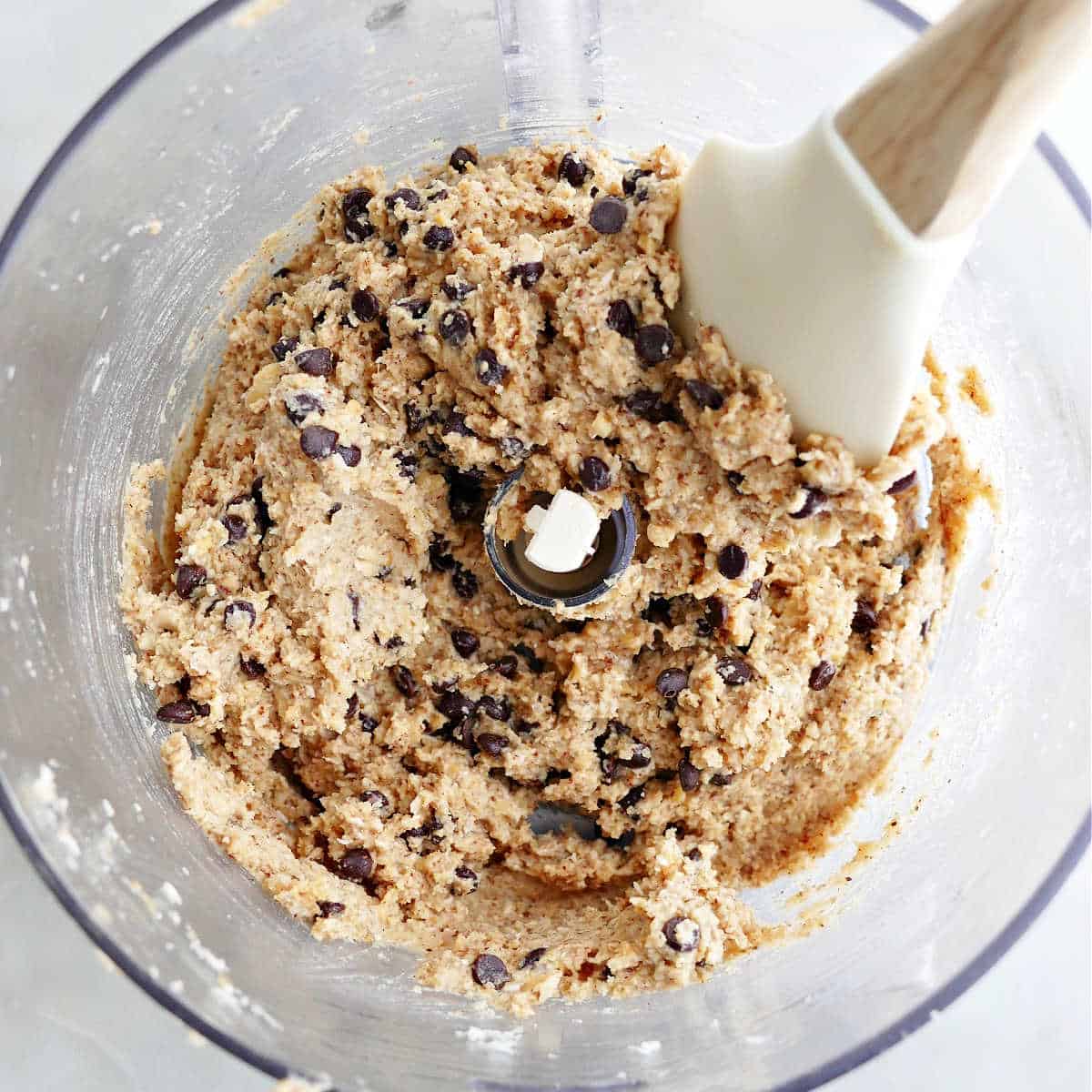 mini chocolate chips being mixed into chickpea cookie dough in a food processor