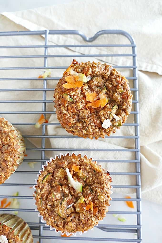 two zucchini carrot oat muffins on a metal cooling rack over a napkin