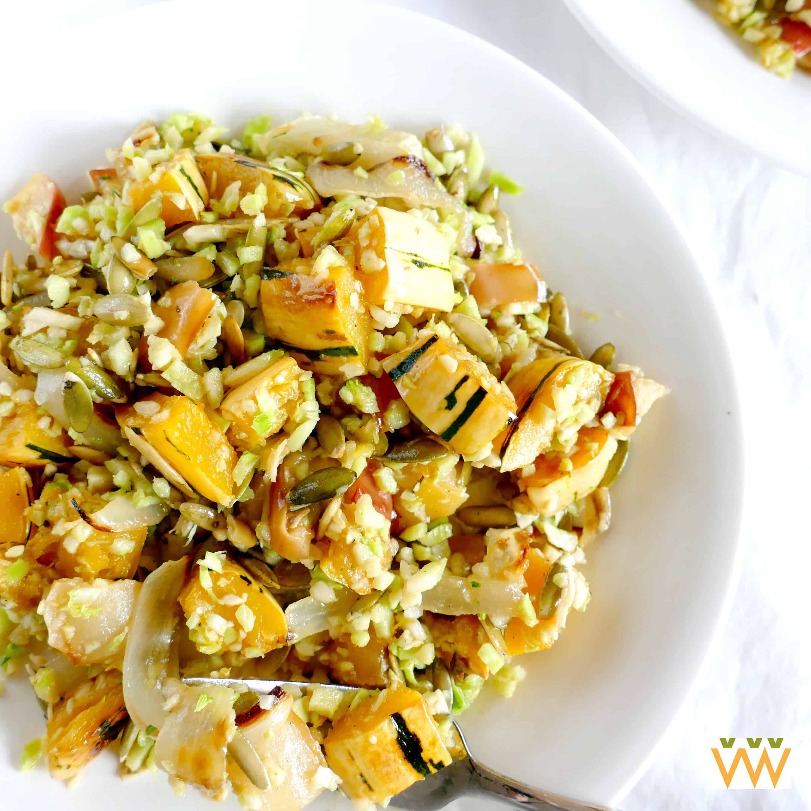 Riced broccoli and veggies in a white bowl with a fork. 