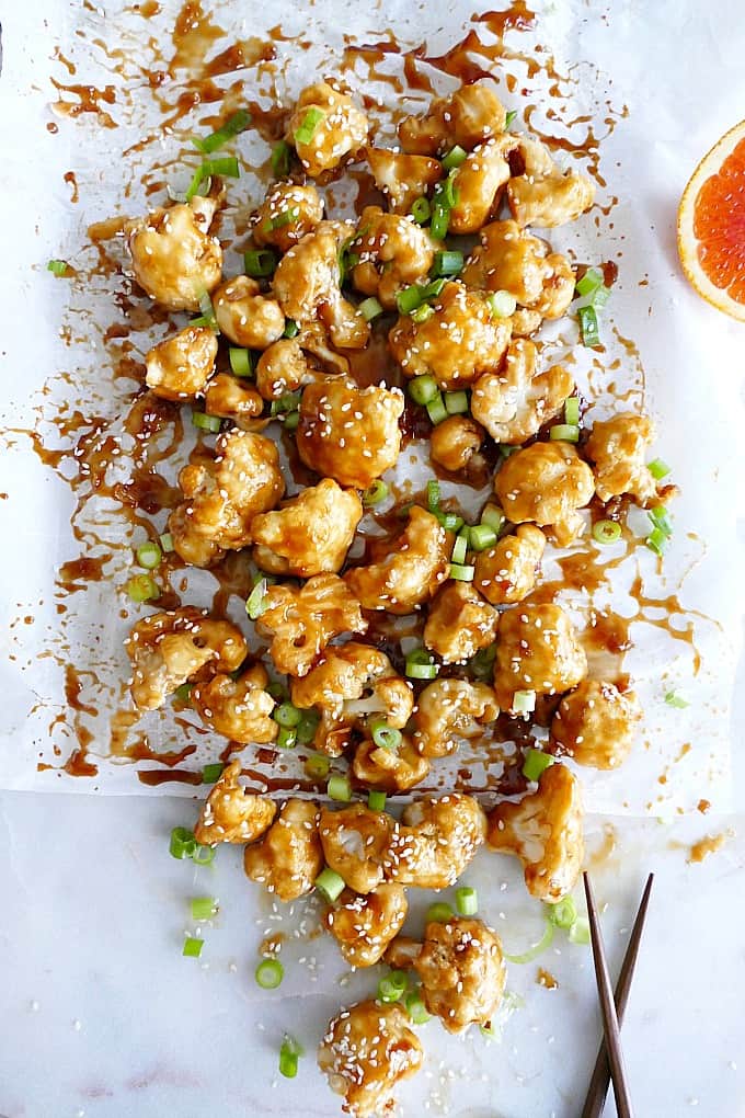 roasted sticky orange cauliflower on a white counter topped with scallions and sesame seeds
