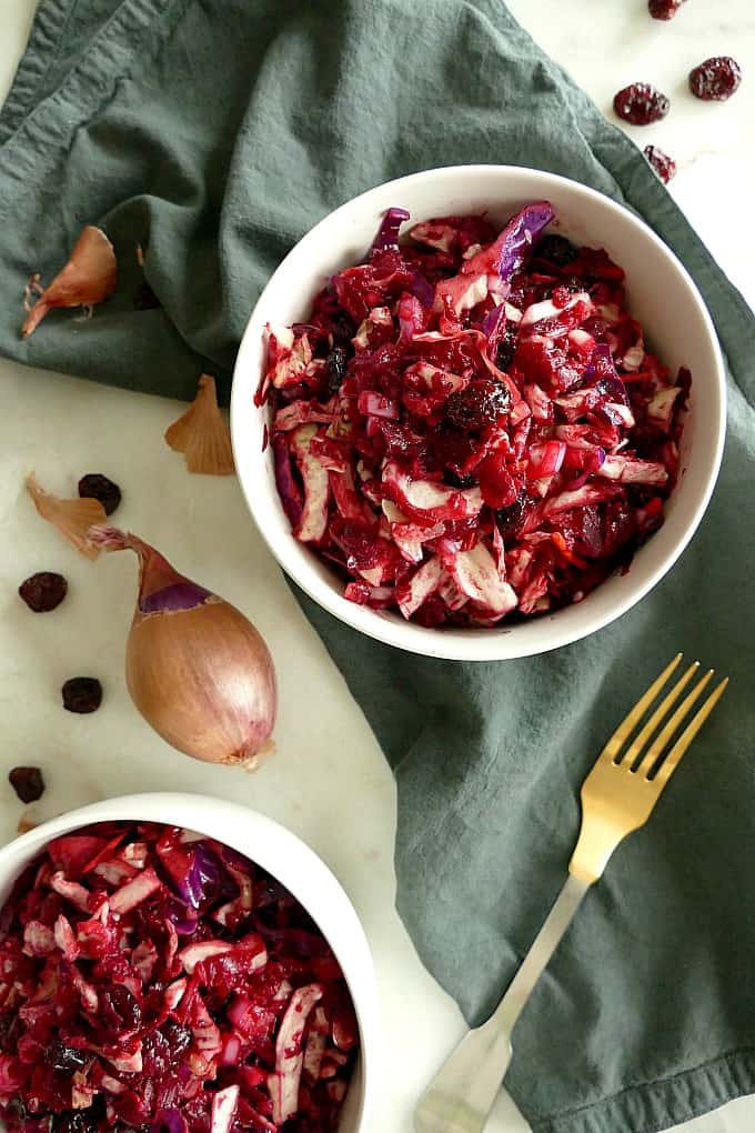 2 bowls of red cabbage slaw on a blue napkin on a white counter