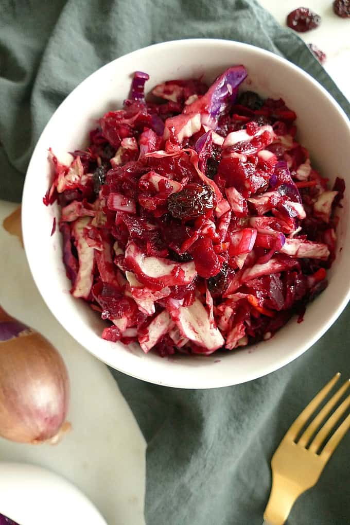 vegan red cabbage slaw with beets in a white bowl on top of a blue napkin