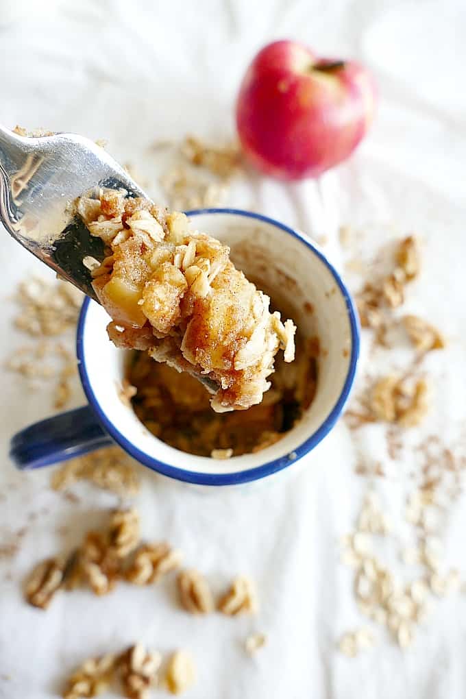 silver fork with a bite of microwave apple crisp on it over a mug