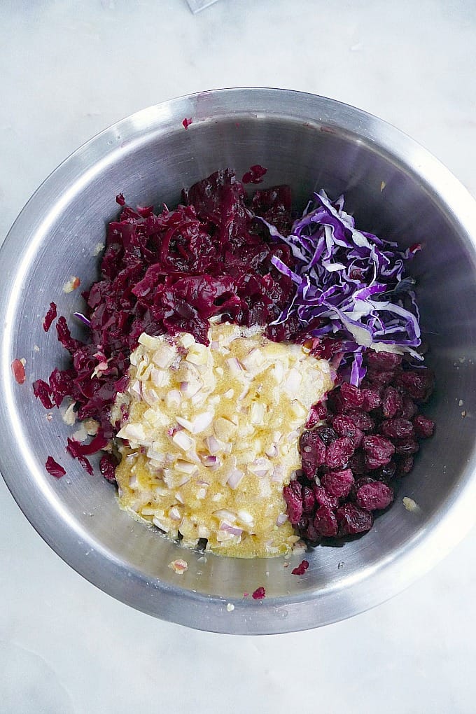 ingredients for red cabbage slaw with apples and dried cranberries in a mixing bowl