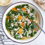 bowl of white bean, sausage, and kale soup topped with parmesan cheese