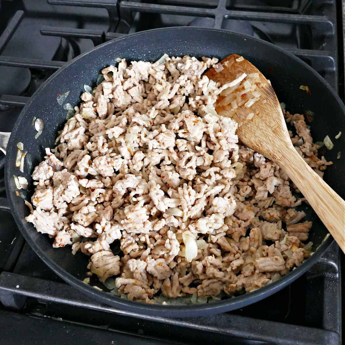 ground turkey being browned in a skillet with onion on a stovetop