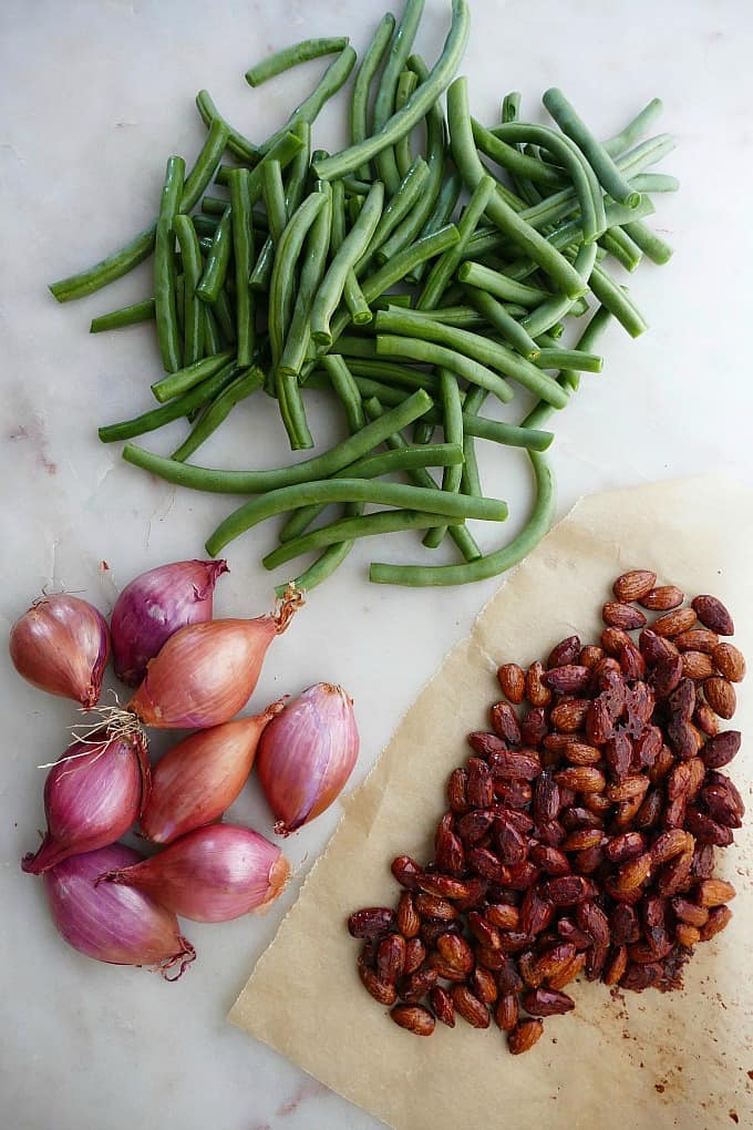 green beans, shallots, and a piece or parchment paper with maple roasted almonds