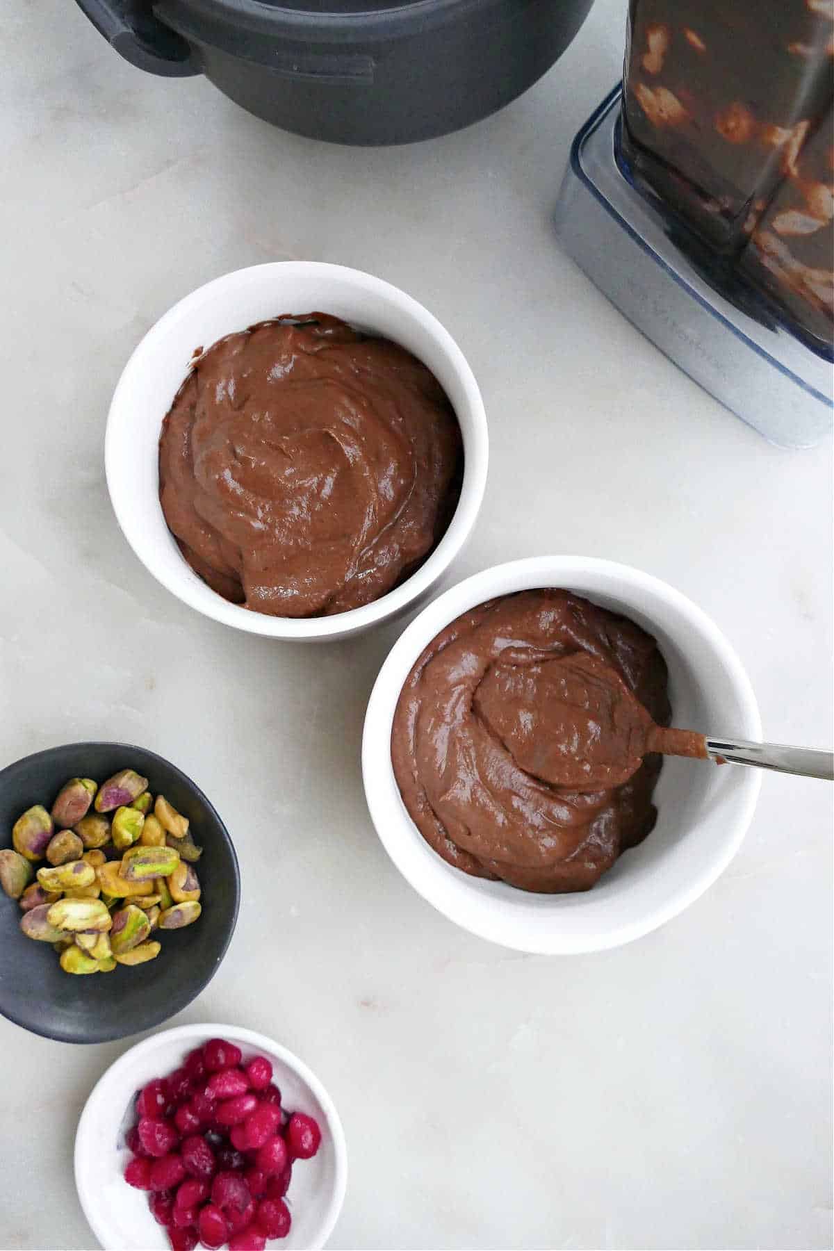 avocado chocolate mousse spooned into serving dishes next to toppings
