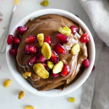 Vegan avocado chocolate mousse in a serving bowl with pistachios and pomegranate arils