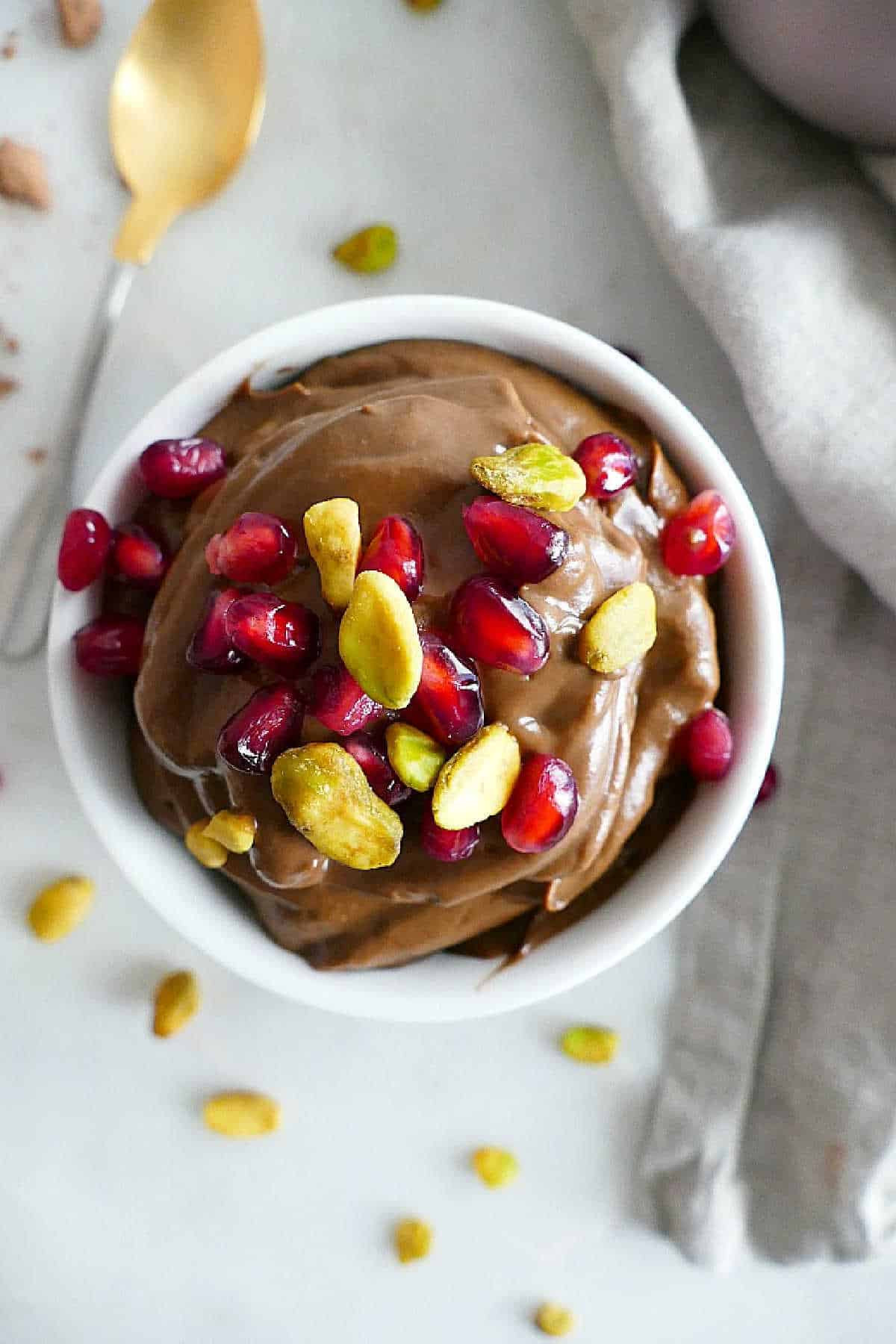 Vegan avocado chocolate mousse in a serving bowl with pistachios and pomegranate arils