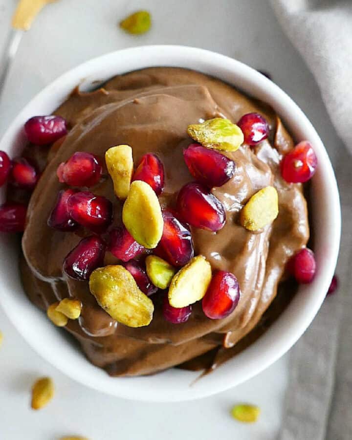 avocado chocolate mousse topped with pistachios and pomegranate arils in a serving bowl