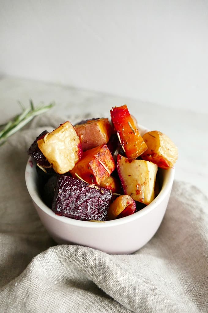 close-up shot of savory roasted root vegetables in a small pink bowl on gray napkin