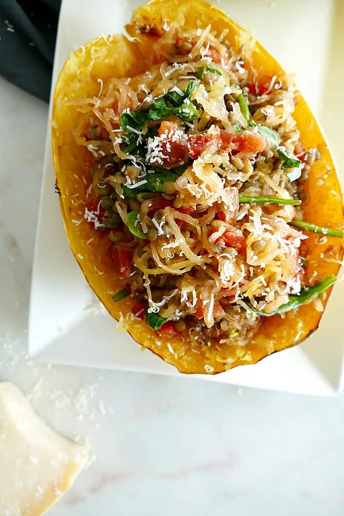 spaghetti squash stuffed with tomatoes, lentils, and spinach on a white plate