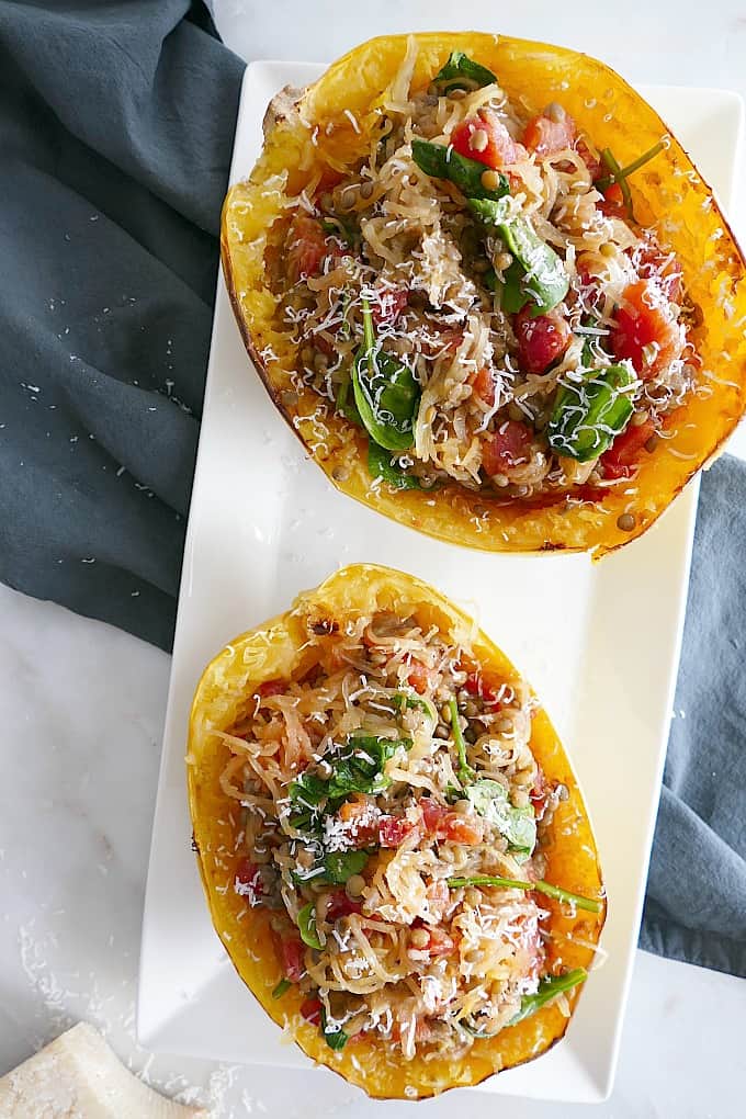 two vegetarian italian spaghetti squash boats on a white tray on a blue napkin