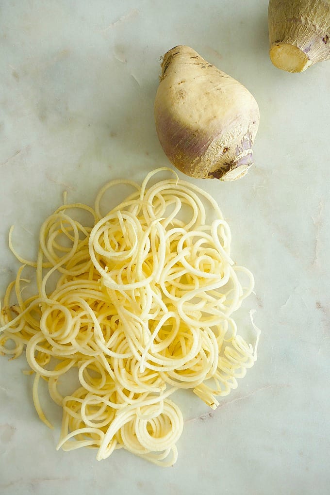 rutabaga noodles on a counter next to a whole rutabaga