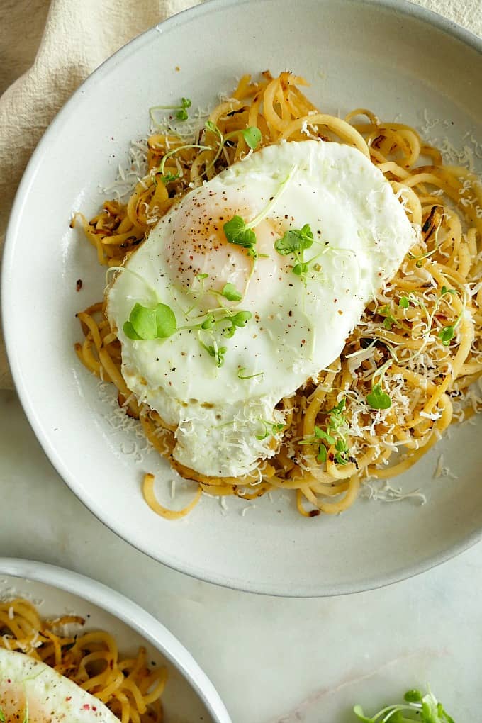 rutabaga noodles on a plate topped with an egg, greens, and cheese