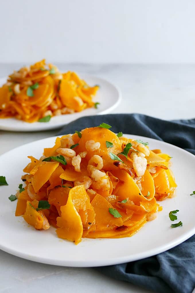 side angle of Butternut Squash Noodles and Shrimp on a white plate on a blue napkin