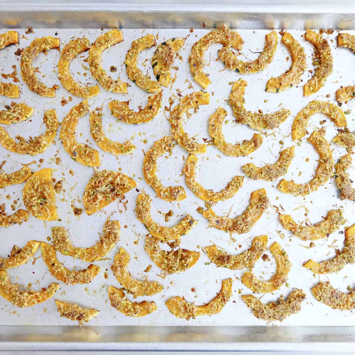 Crispy parmesan delicata squash slices on a baking sheet after roasting.