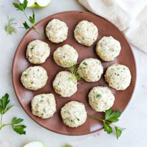 12 apple chicken meatballs on a serving plate with parsley.