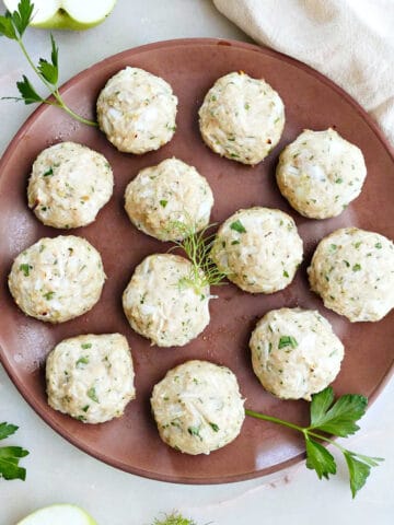 12 apple chicken meatballs on a serving plate with parsley.