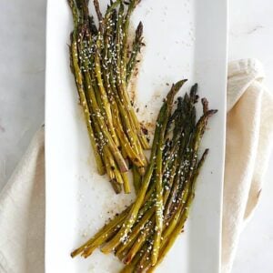 roasted sesame asparagus separated into two bunches on a white serving platter