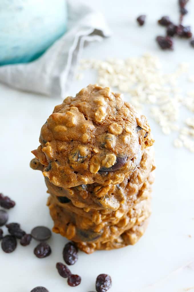 Overhead view of a stack of sweet potato cookies next to oats and raisins