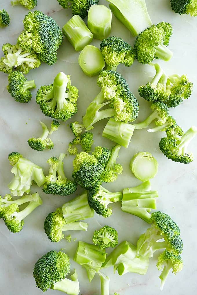 broccoli florets and stalks scattered across a white countertop