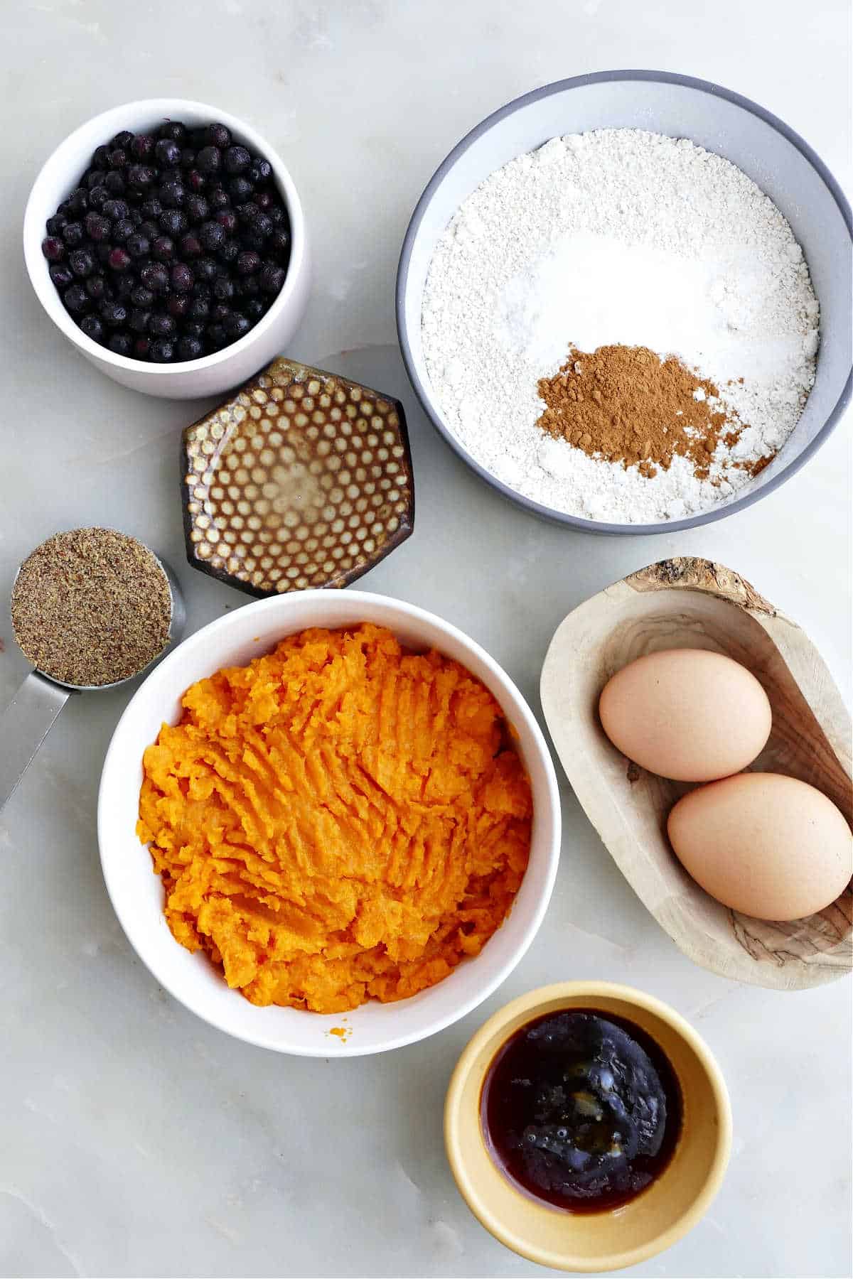 Mashed sweet potato, flaxseed, oats, eggs, and other ingredients for muffins.