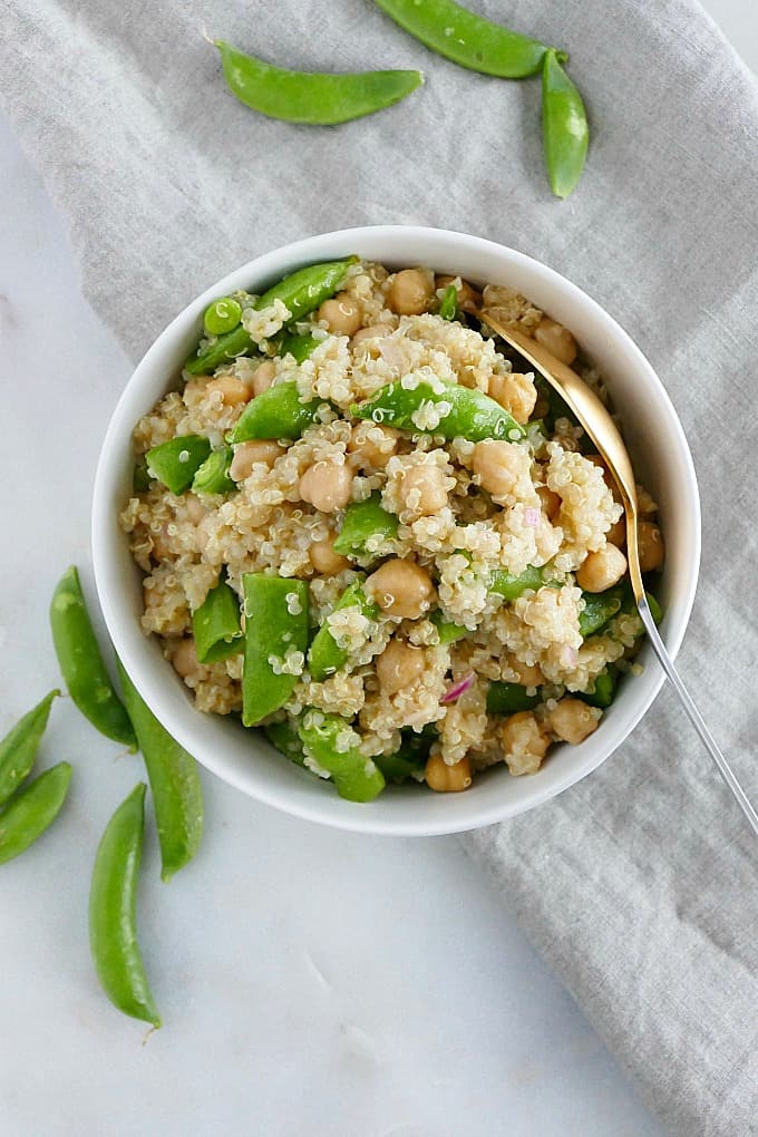sugar snap pea quinoa salad in a bowl with a spoon on a counter