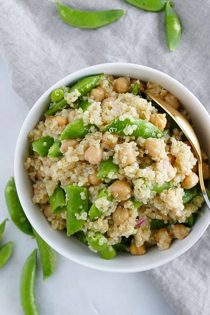 bowl of sugar snap pea quinoa salad with a spoon on top of a napkin