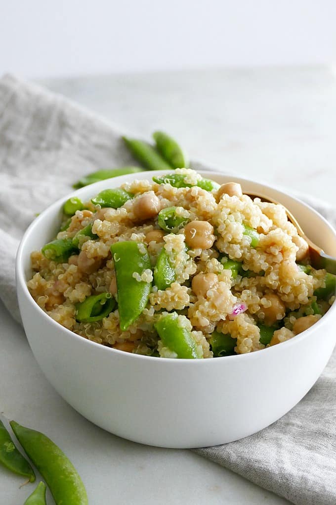 side view of quinoa mixed with sugar snap peas and chickpeas on a counter