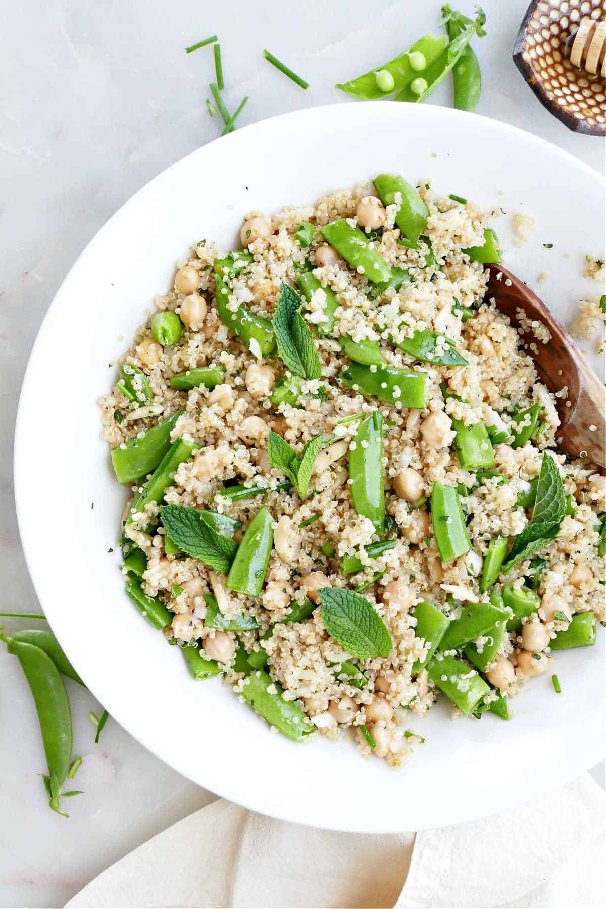 side view of quinoa mixed with sugar snap peas and chickpeas on a counter