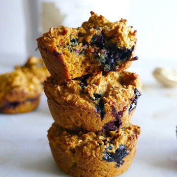 Three sweet potato blueberry muffins stacked on top of each other.