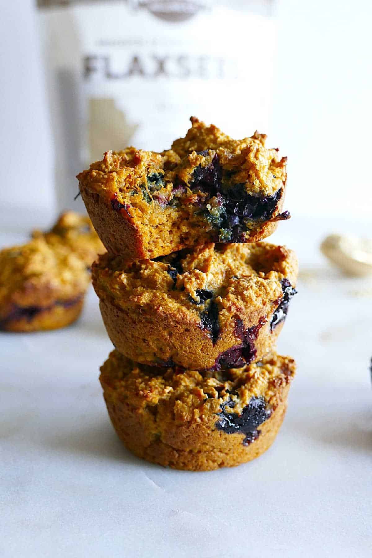 three sweet potato blueberry muffins stacked on top of each other on a counter