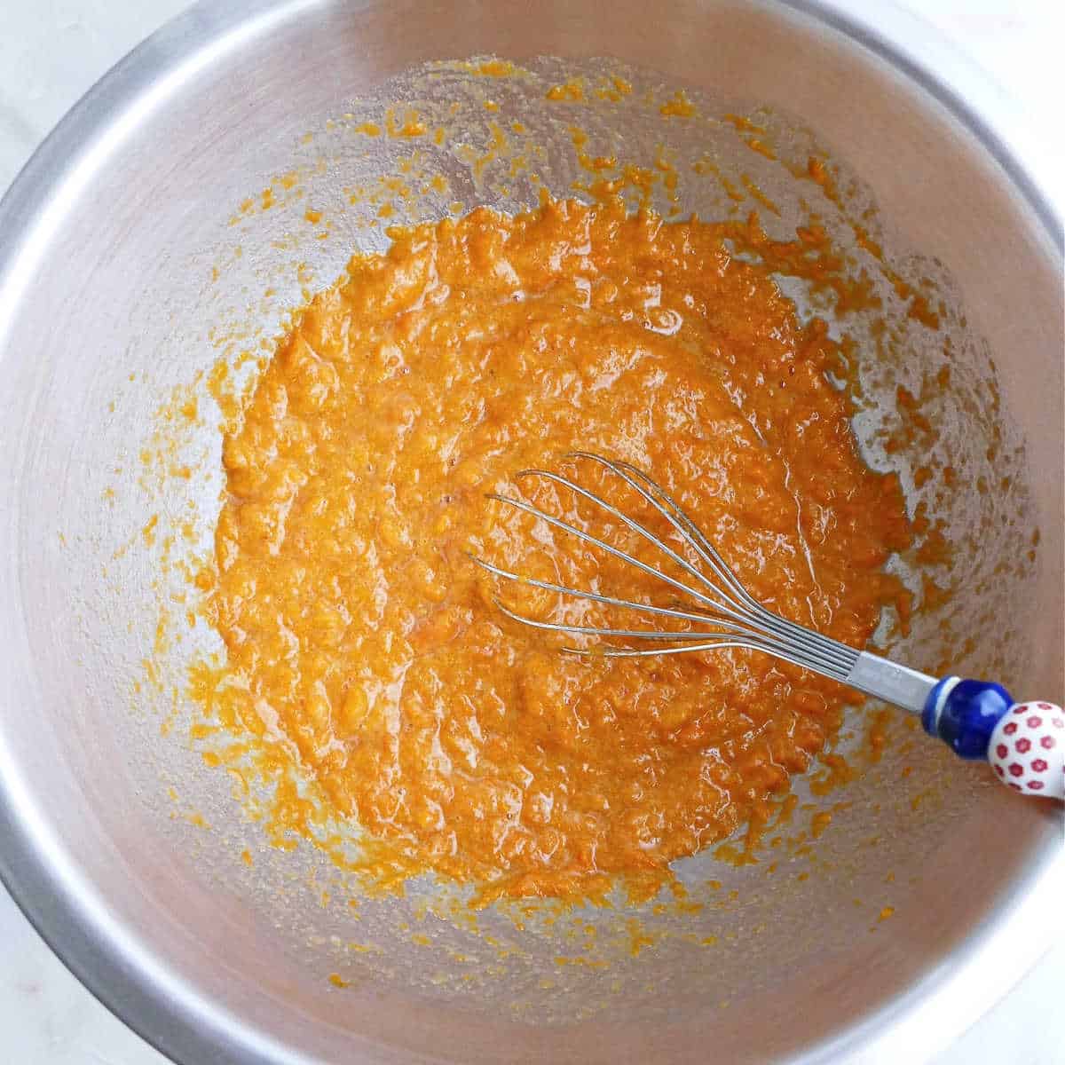 sweet potato mixed with other wet ingredients for muffins in a bowl