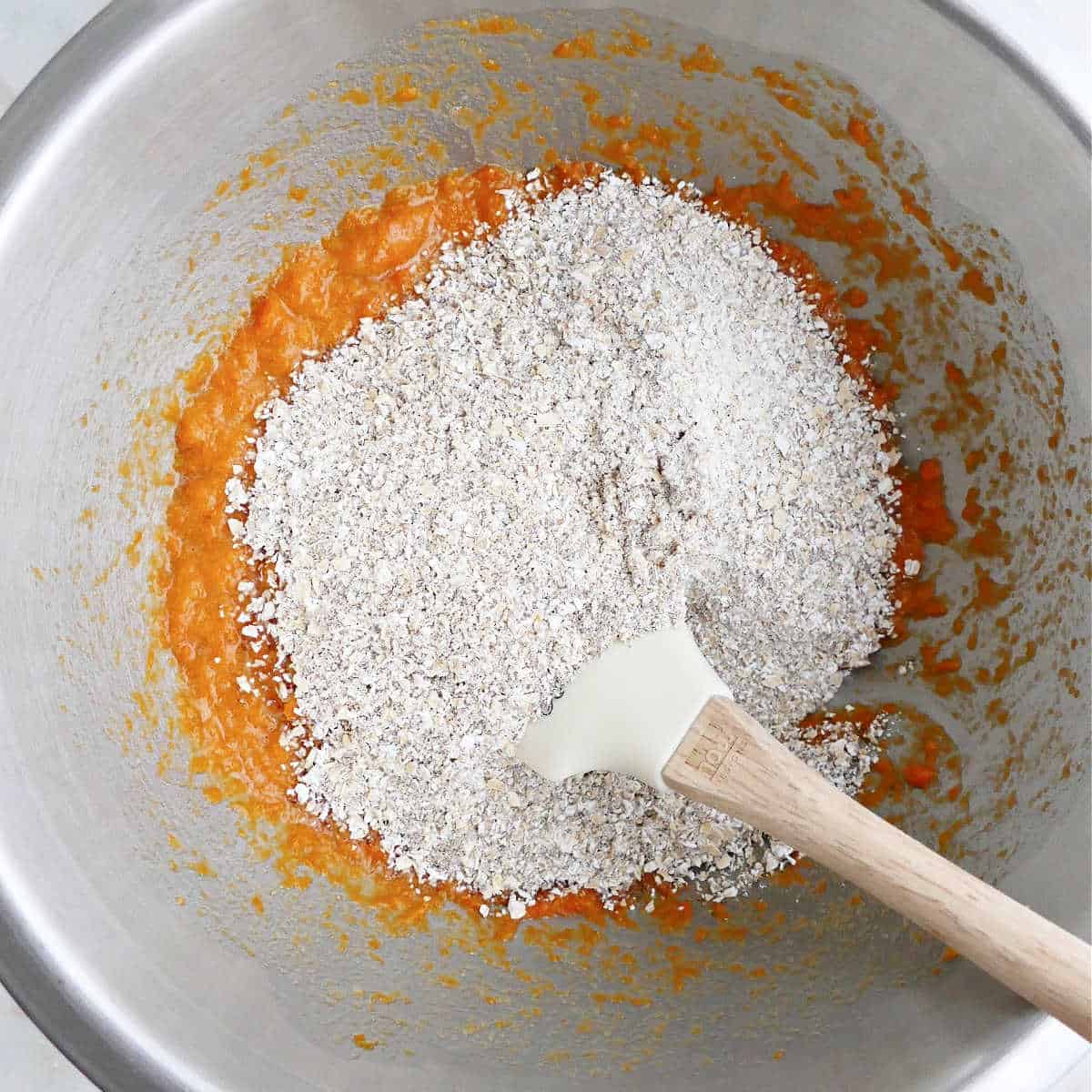 dry ingredients on top of the wet ones for muffins in a mixing bowl