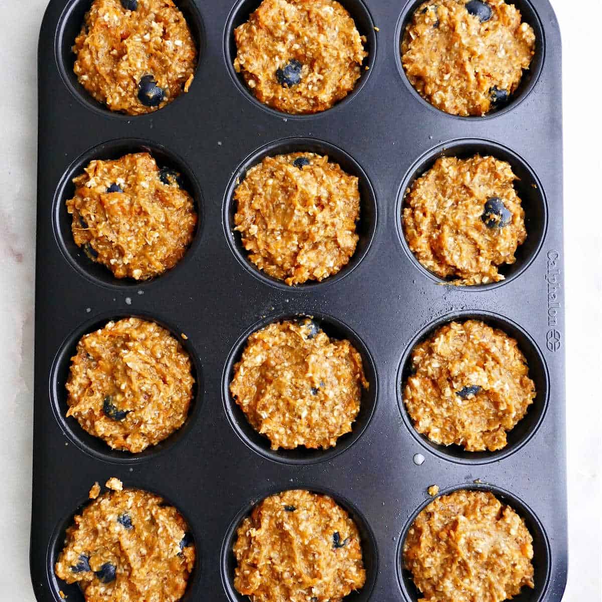 a muffin tin filled with batter for sweet potato muffins on a counter