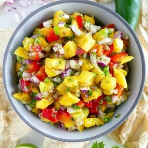 fresh mango salsa in a serving bowl surrounded by ingredients on a counter