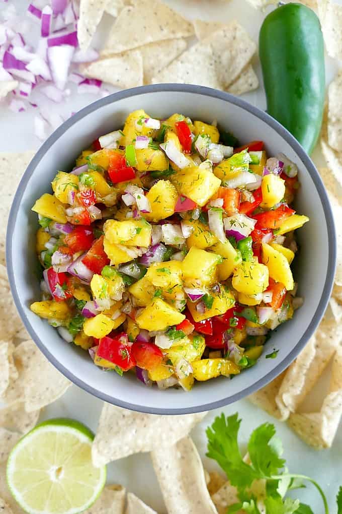 close up shot of mango salsa sprinkled with dill and cilantro on counter