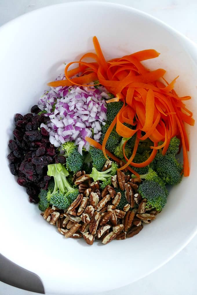 ingredients for broccoli salad in a white mixing bowl