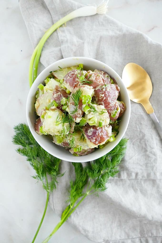 white bowl with vegan potato salad centered on a gray napkin on a counter top