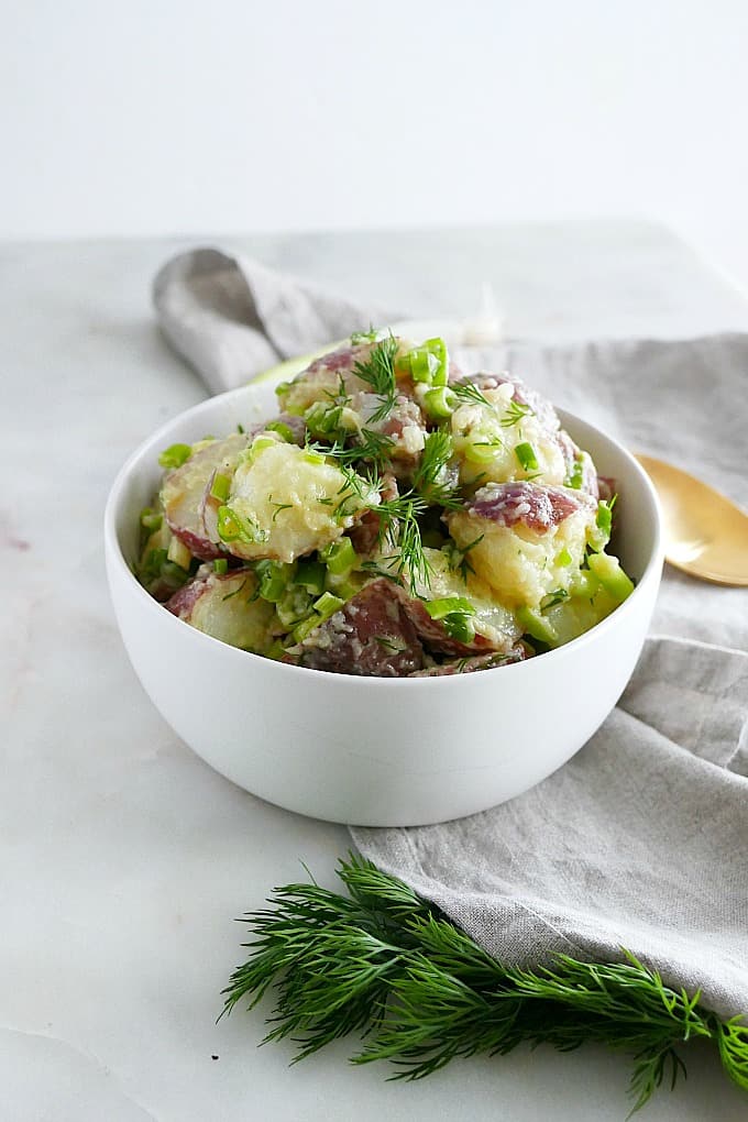 healthy scallion dill potato salad in a serving bowl on a counter