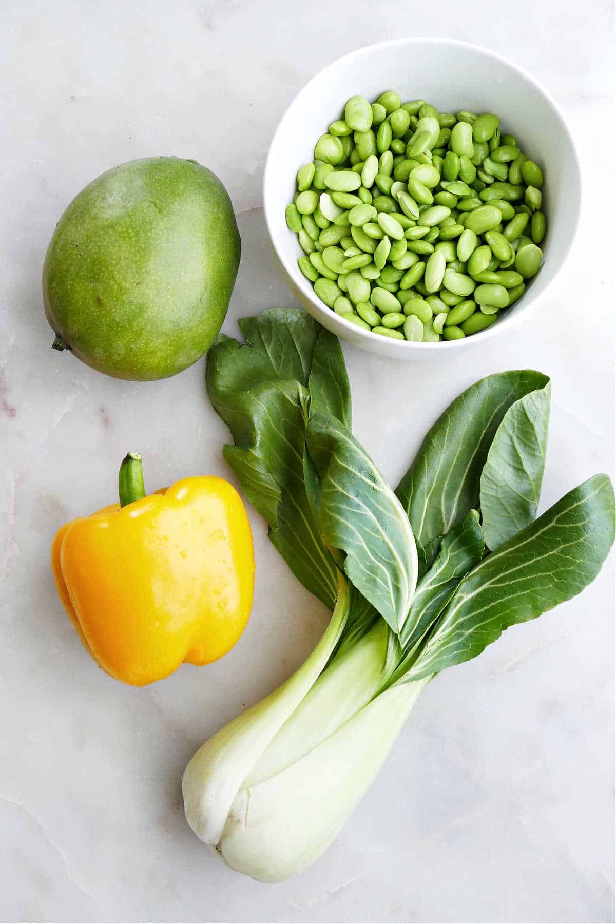 mango, bell pepper, edamame, and bok choy next to each other on a counter