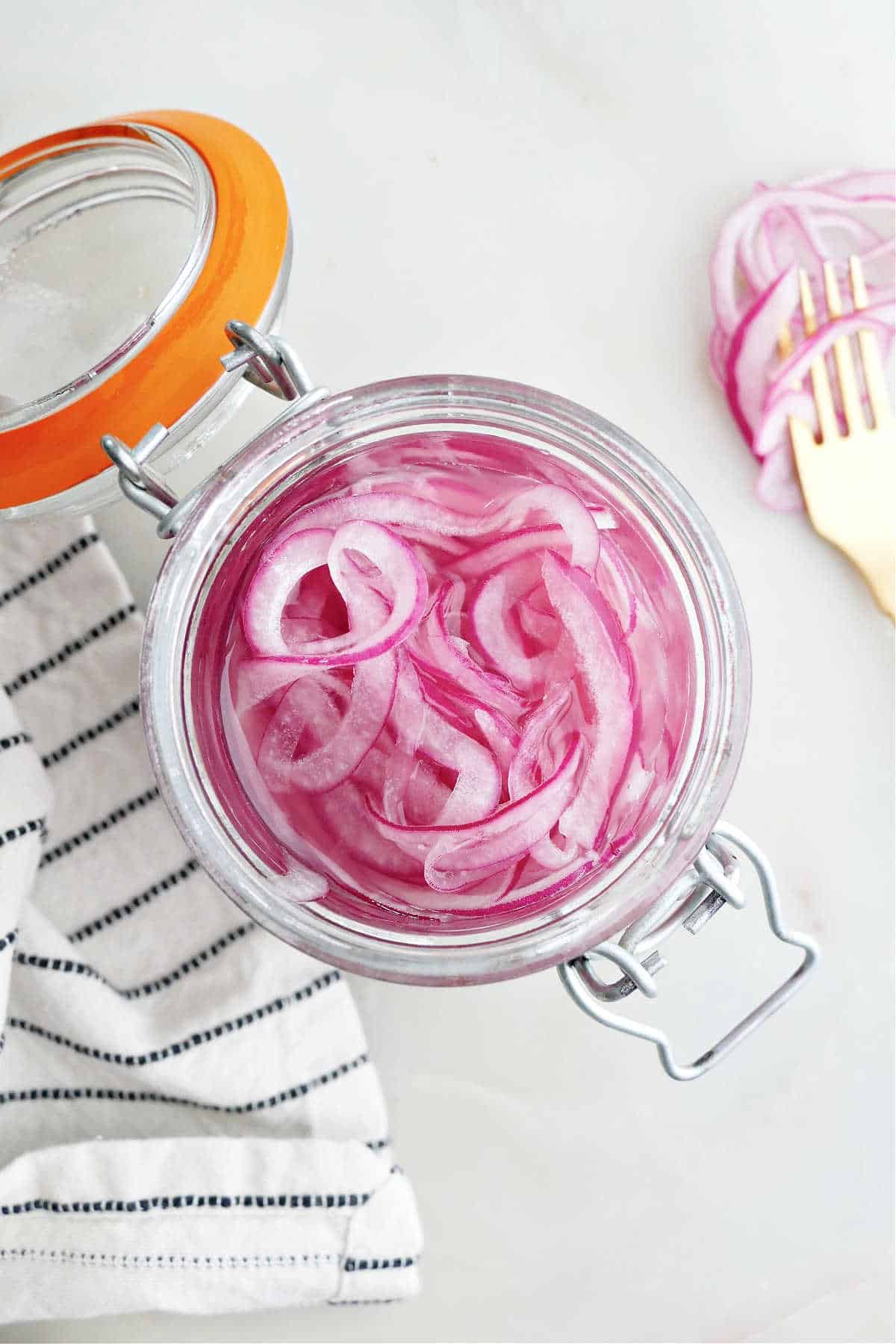 overhead view of pickled red onions in brine in a jar