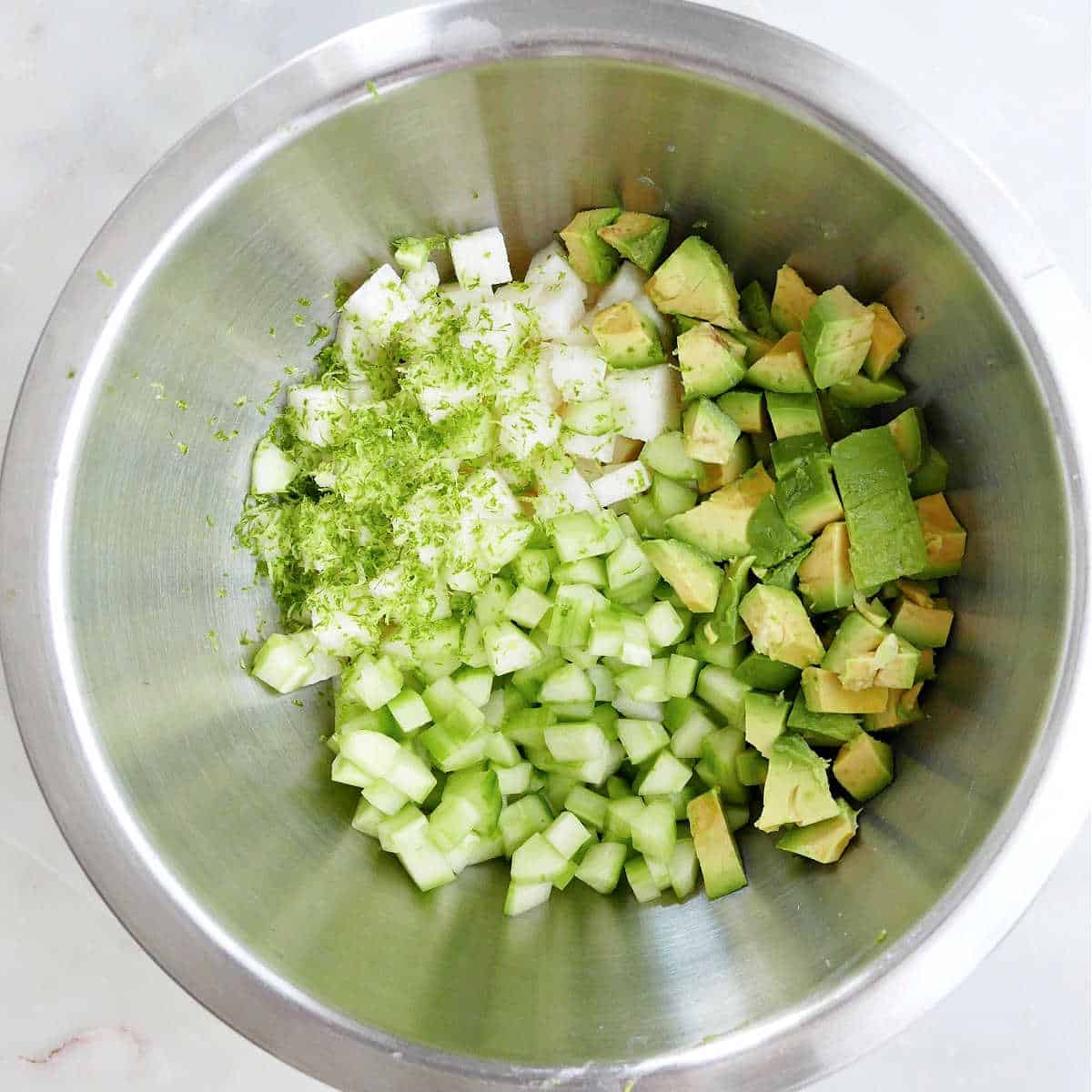 ingredients for jicama cucumber salad in a mixing bowl before being stirred together