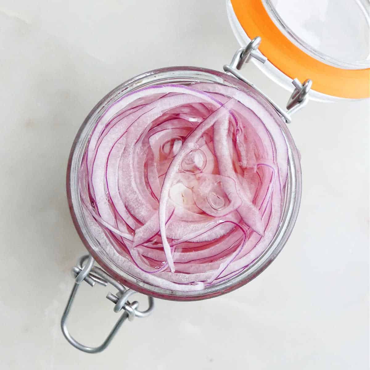 thinly sliced red onion in a jar before being covered in vinegar brine