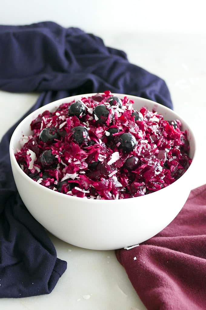 side view of festive beet slaw in a white dish with blueberries and coconut